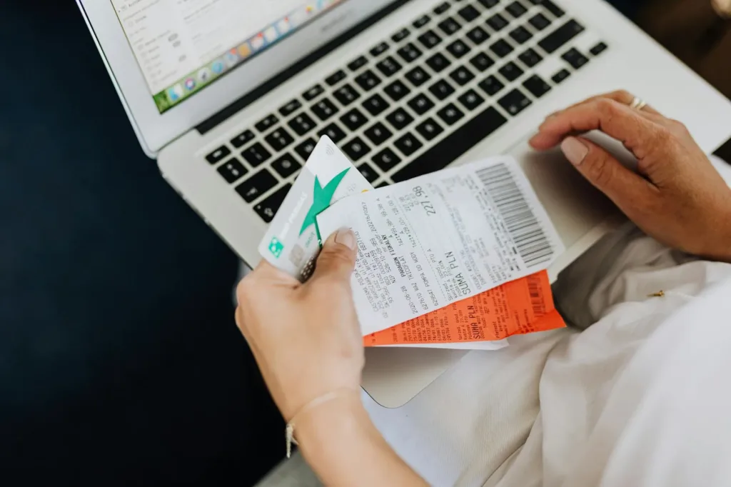 person using a computer and holding a credit card and receipts